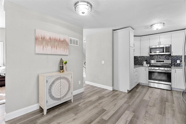 kitchen with visible vents, white cabinets, light countertops, appliances with stainless steel finishes, and decorative backsplash