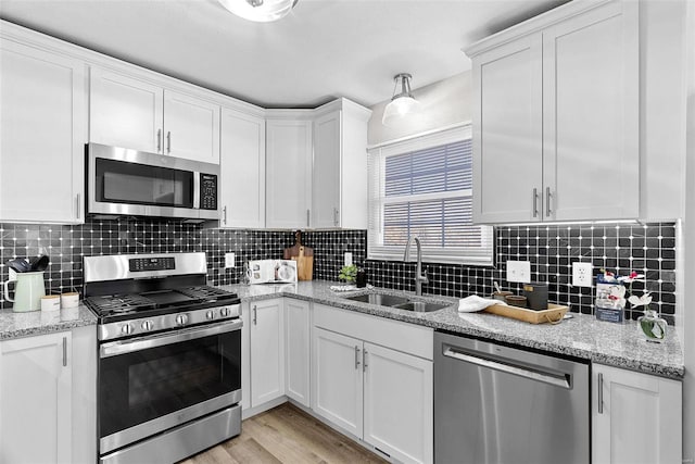 kitchen featuring white cabinetry, appliances with stainless steel finishes, tasteful backsplash, and a sink