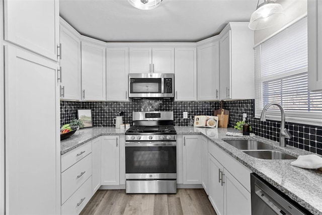 kitchen with stainless steel appliances, a sink, white cabinetry, and light wood-style floors