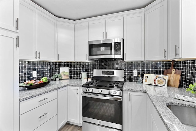 kitchen with stainless steel appliances, white cabinets, and decorative backsplash