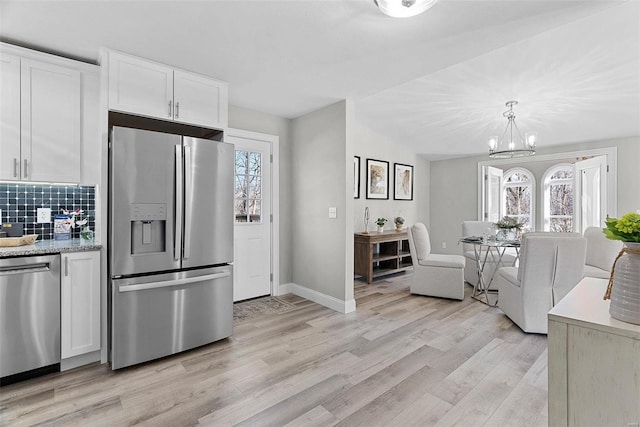 kitchen featuring white cabinets, light countertops, appliances with stainless steel finishes, backsplash, and light wood finished floors