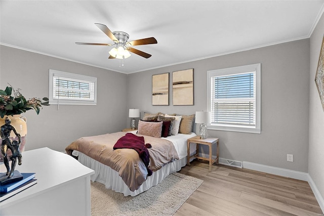 bedroom with light wood-style floors, crown molding, and baseboards