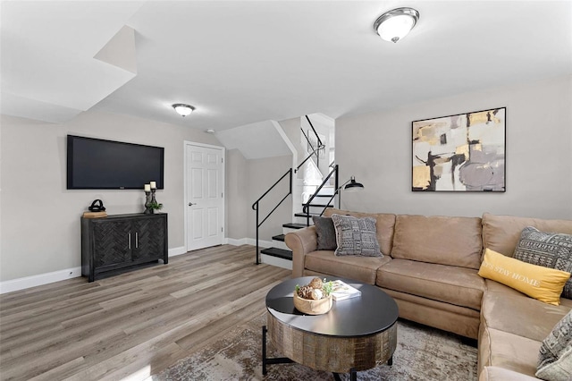 living room with stairs, vaulted ceiling, light wood-style flooring, and baseboards