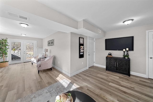 living room with light wood-type flooring, visible vents, and baseboards