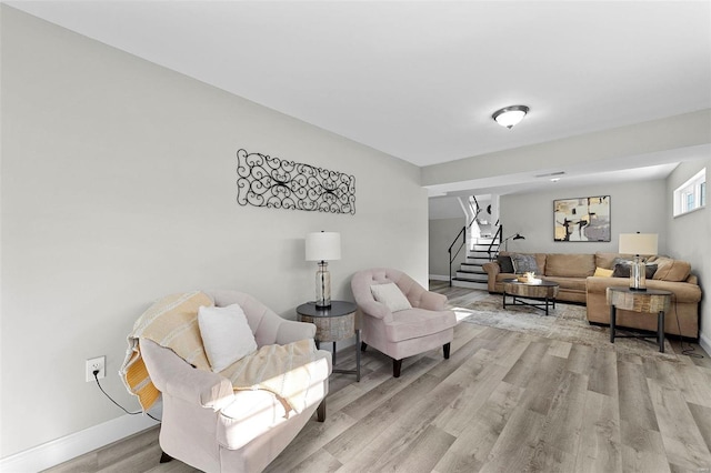 living room featuring stairway, light wood-type flooring, and baseboards