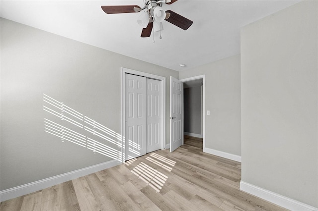 unfurnished bedroom featuring a closet, wood finished floors, a ceiling fan, and baseboards