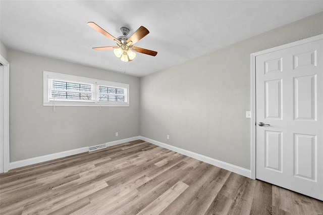 empty room with baseboards, ceiling fan, visible vents, and light wood finished floors