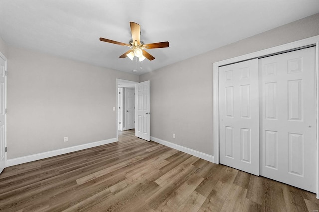 unfurnished bedroom with a closet, ceiling fan, baseboards, and wood finished floors