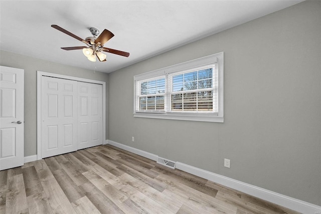 unfurnished bedroom with a closet, light wood-style flooring, and baseboards