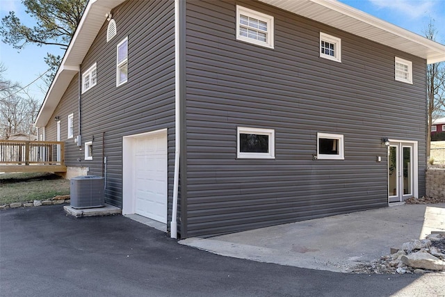 view of side of home with driveway, a wooden deck, and central air condition unit