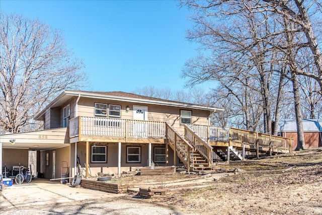 rear view of property with stairs, driveway, and an attached carport