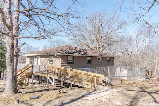 rear view of property featuring fence, stairway, and a wooden deck