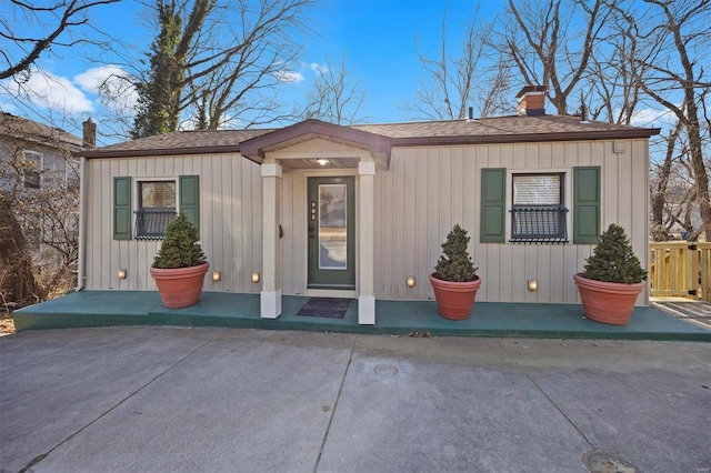 exterior space with a shingled roof, a chimney, and board and batten siding