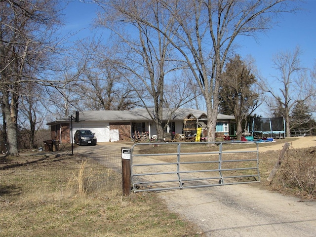 view of front of house featuring a trampoline, a gate, and driveway