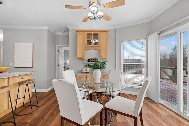 dining area with visible vents, ornamental molding, ceiling fan, wood finished floors, and baseboards