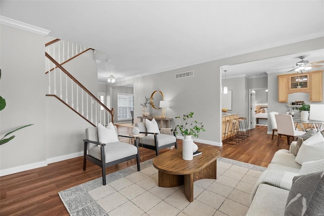 living area featuring visible vents, baseboards, stairs, light wood-type flooring, and crown molding