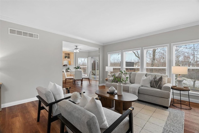 living area featuring light wood-type flooring, baseboards, visible vents, and crown molding