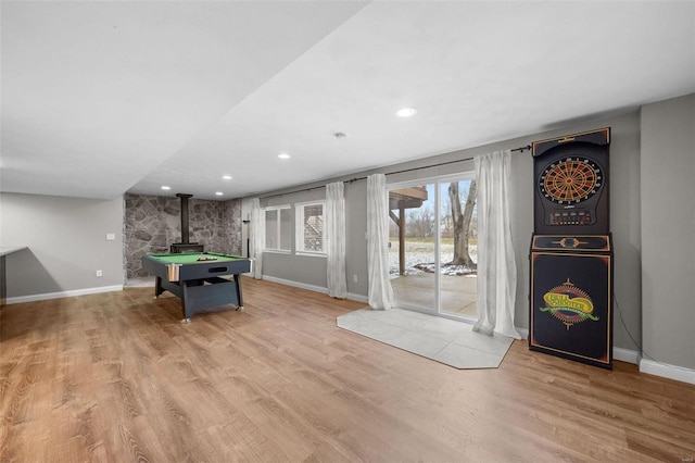 rec room featuring a wood stove, baseboards, and wood finished floors