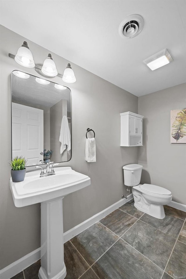 half bathroom with visible vents, toilet, and baseboards