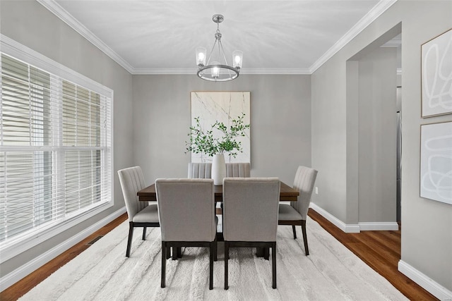 dining area featuring a chandelier, ornamental molding, baseboards, and wood finished floors