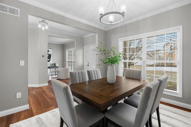 dining room with a healthy amount of sunlight, wood finished floors, visible vents, and a notable chandelier