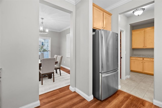 kitchen with baseboards, ornamental molding, freestanding refrigerator, light wood-style floors, and light brown cabinets