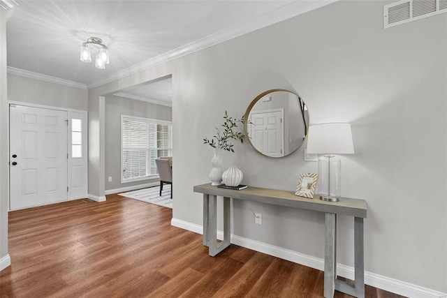 entrance foyer featuring ornamental molding, visible vents, baseboards, and wood finished floors