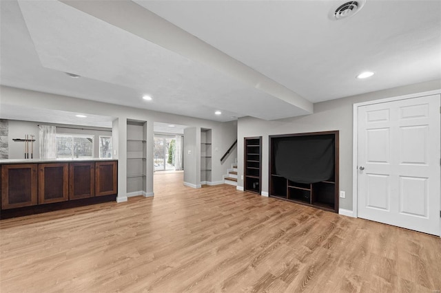 interior space featuring light wood finished floors, visible vents, stairway, and baseboards