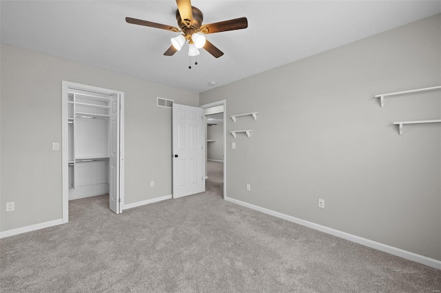 unfurnished bedroom with a walk in closet, visible vents, carpet flooring, ceiling fan, and baseboards