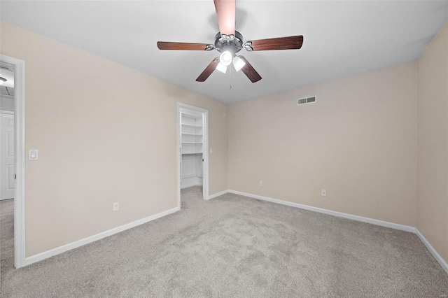 carpeted spare room with visible vents, ceiling fan, and baseboards