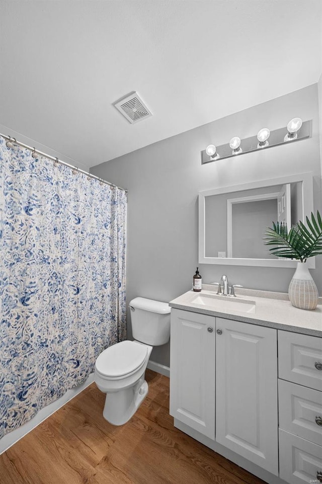 full bath featuring visible vents, a shower with shower curtain, toilet, wood finished floors, and vanity