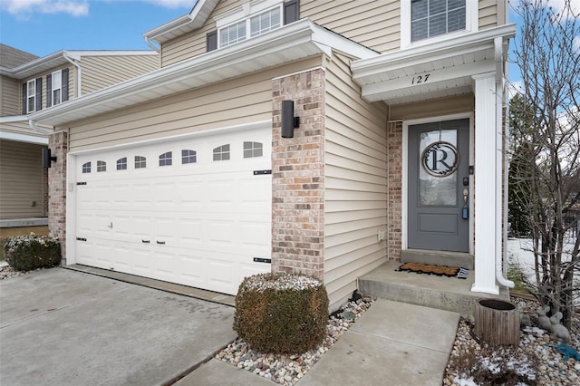 entrance to property with driveway, an attached garage, and brick siding