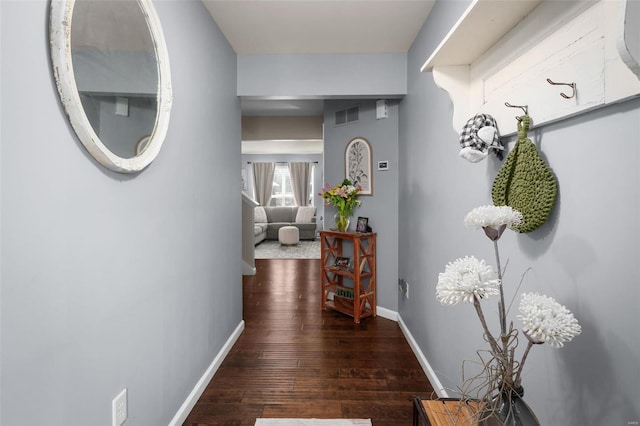 corridor featuring baseboards, visible vents, and hardwood / wood-style floors