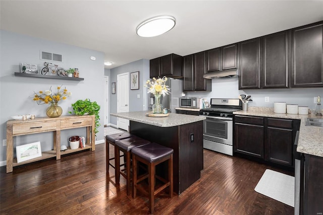 kitchen with stainless steel appliances, dark wood-type flooring, visible vents, a center island, and a kitchen bar