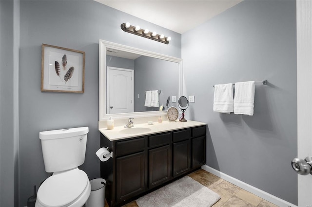 bathroom featuring toilet, baseboards, and vanity