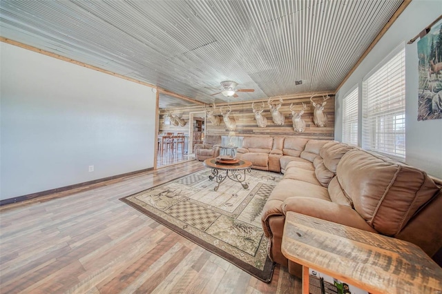 living area featuring wood finished floors, baseboards, and ceiling fan