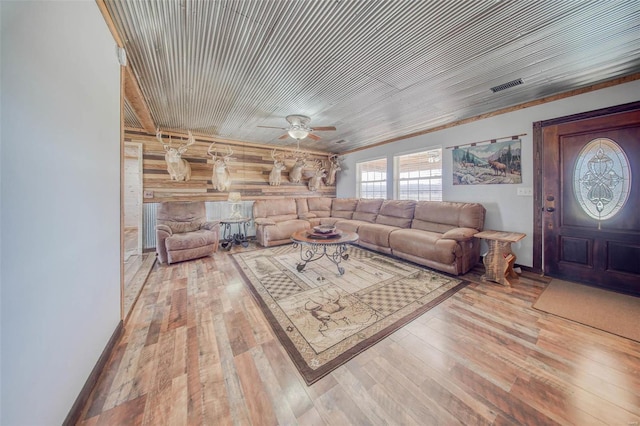 unfurnished living room featuring visible vents, wood walls, a ceiling fan, and wood-type flooring