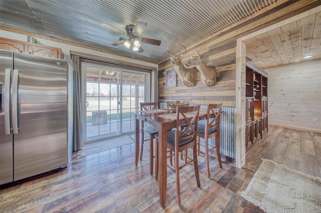 dining space featuring ceiling fan, wood finished floors, wooden ceiling, and wood walls