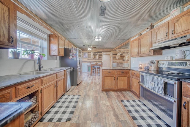 kitchen with visible vents, light wood-type flooring, under cabinet range hood, a sink, and appliances with stainless steel finishes