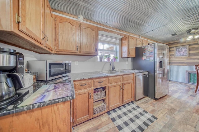 kitchen with a sink, appliances with stainless steel finishes, wood walls, light wood finished floors, and wood ceiling