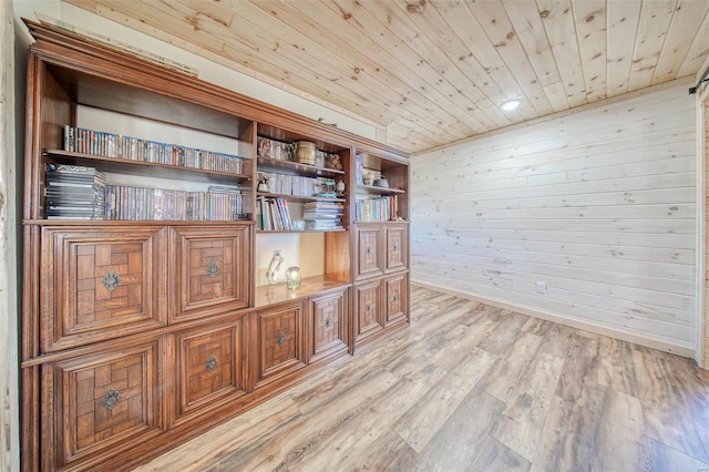 unfurnished office featuring wood walls, wood ceiling, light wood-type flooring, and baseboards