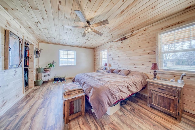 bedroom featuring wooden walls, wood ceiling, wood finished floors, and a ceiling fan