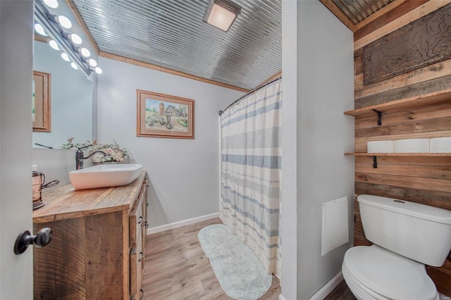 full bathroom featuring wooden walls, toilet, vanity, and wood finished floors