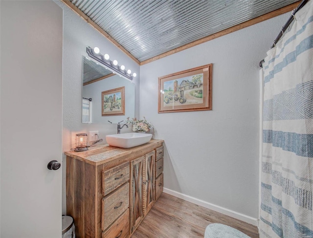 bathroom with vanity, a shower with curtain, wood finished floors, baseboards, and crown molding