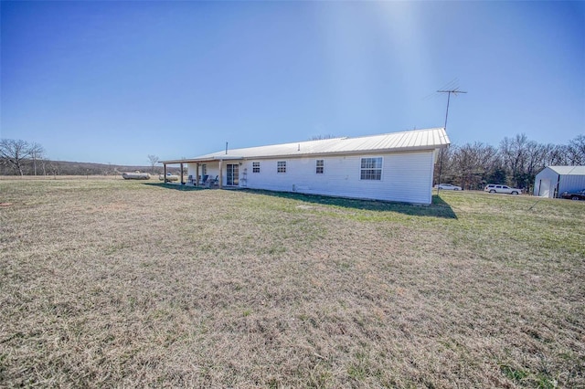 back of property featuring a yard and metal roof