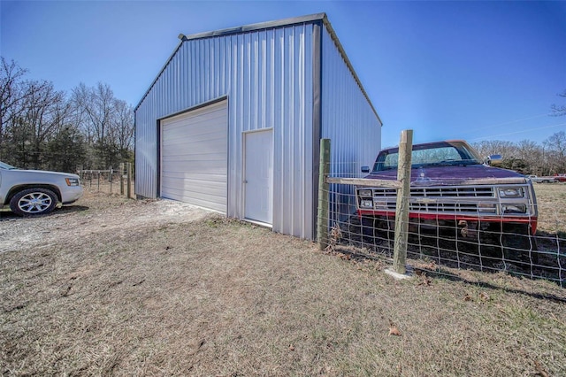 view of outdoor structure with fence, an outdoor structure, and dirt driveway