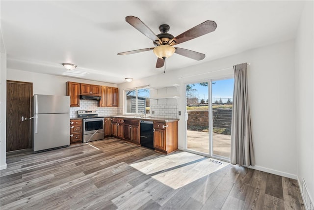 kitchen with visible vents, decorative backsplash, appliances with stainless steel finishes, wood finished floors, and under cabinet range hood