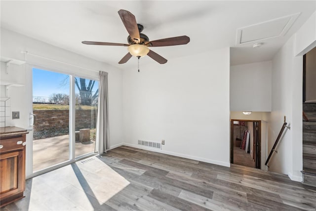 spare room featuring stairway, wood finished floors, visible vents, and baseboards