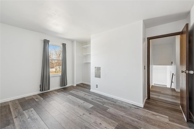 spare room featuring baseboards and wood finished floors