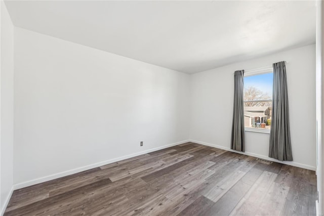 unfurnished room with wood finished floors, visible vents, and baseboards